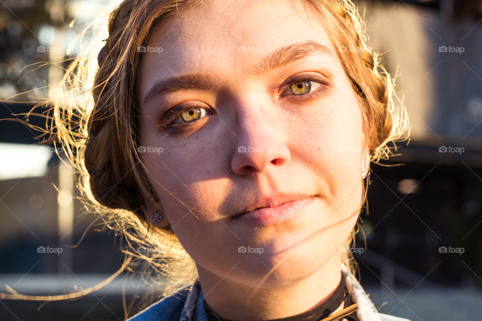 Young woman with braided hair content on a beautiful windy sunny day with unique green eyes and face structure 