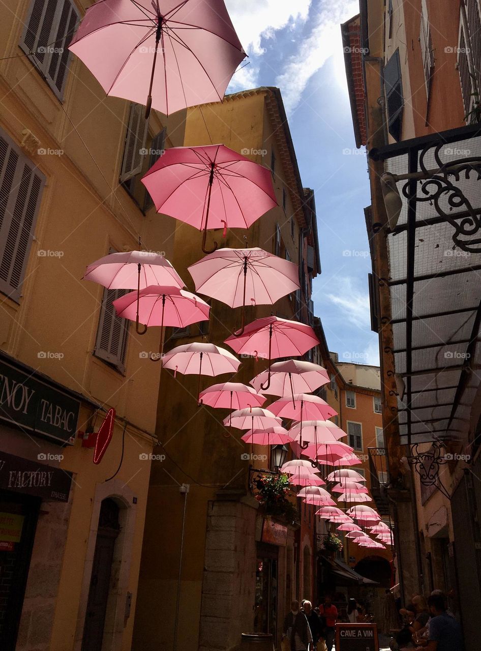 Pinky umbrella line providing shadow in a city narrow street 