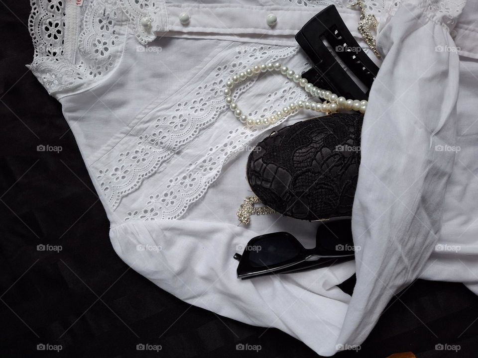 vintage white lace shirt with retro handbag, pearls, glasses on black background