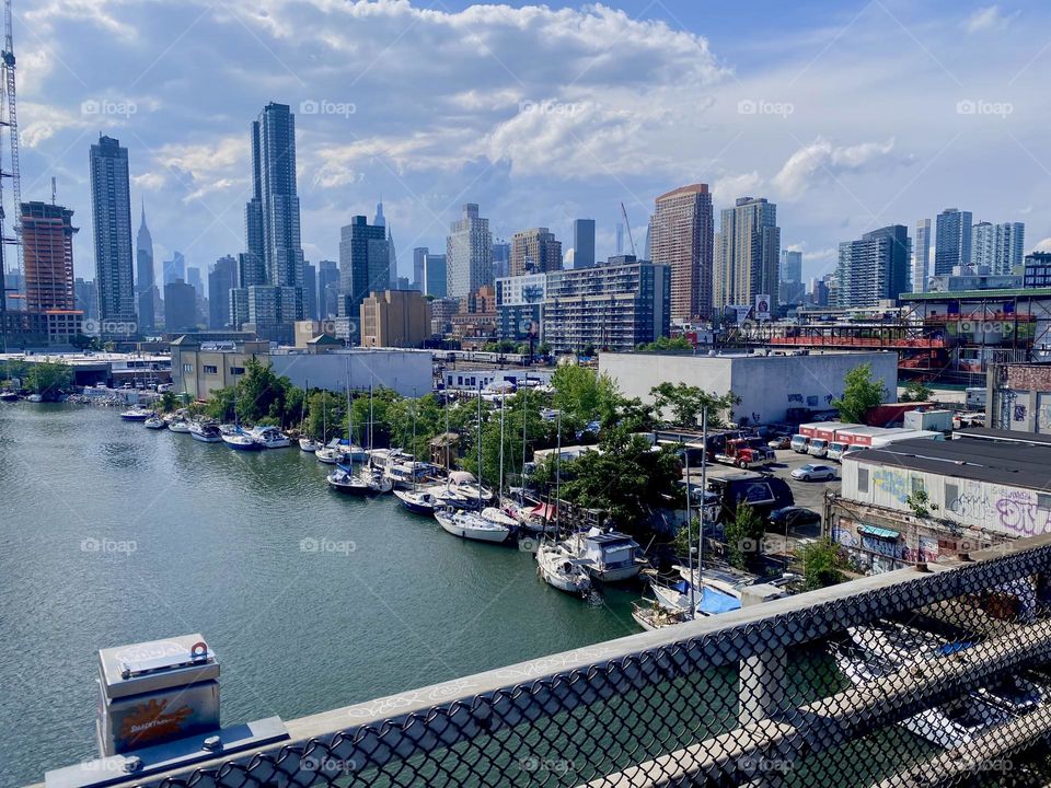 A beautiful view can be enjoyed from here on top of the “Pulaski Bridge” in LIC, Queens. A variety of boats are tied to the shore here from motorboats to sailboats to houseboats. 2023. Hypnotic Productions