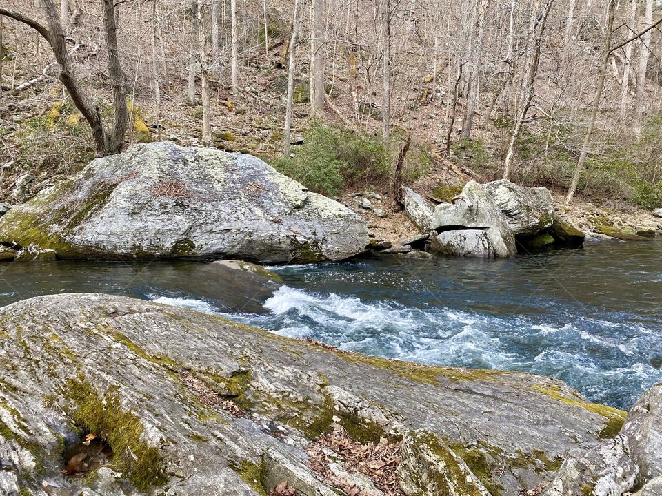 A river surrounded by large moss and lichen covered rocks