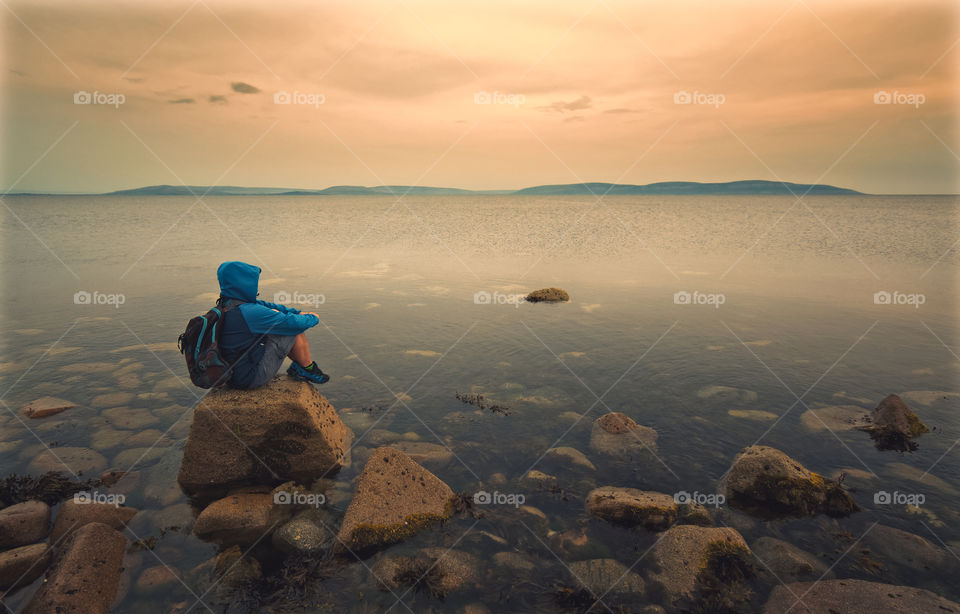 Man sitting on the rock in the Atlantic ocean