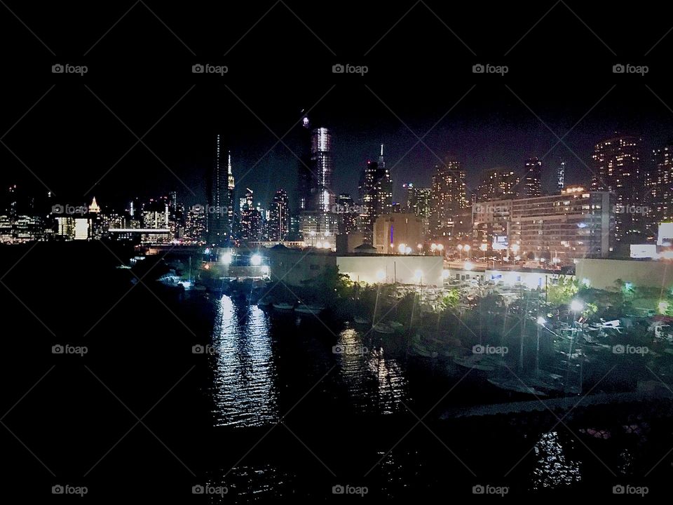 Long Island City, Queens, New York as seen from the Pulaski Bridge at night and in the far distance the Manhattan skyline and the illuminated Empire State Building. Photographed in October 2020. Hypnotic Productions