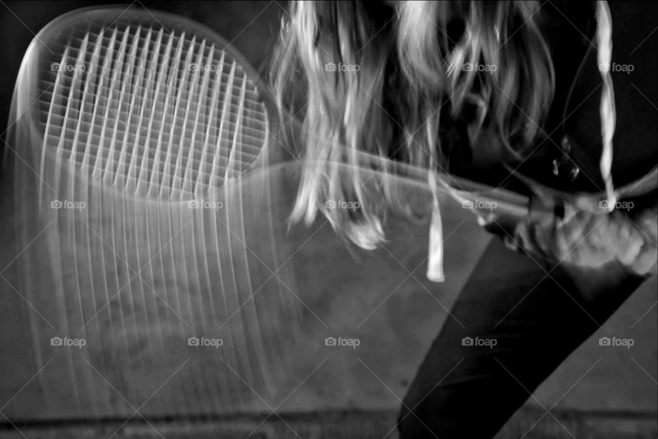 Long exposure of a squash racket being moved by a woman