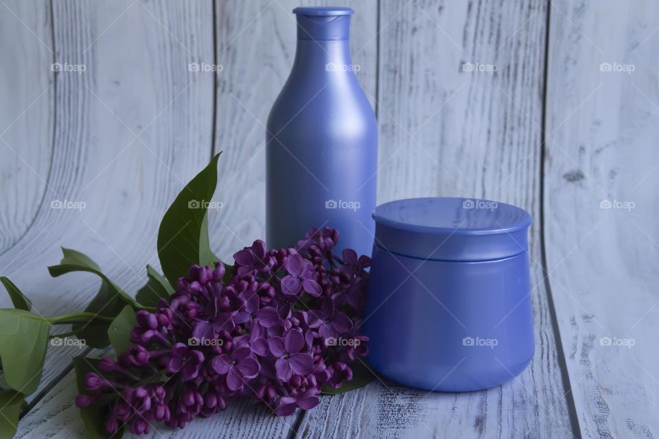 Jars with cosmetic products, beauty cosmetics in purple jars with fragrant flowers.
