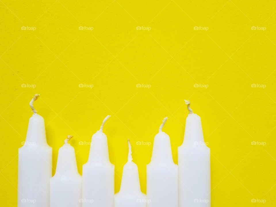 unlit candles on yellow background