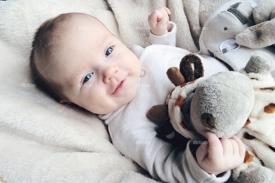 Baby boy lying on bed with teddy bear