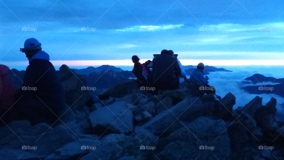 Hikers at the summit of Yarigatake  rest and await the sunrise in the early morning twilight.