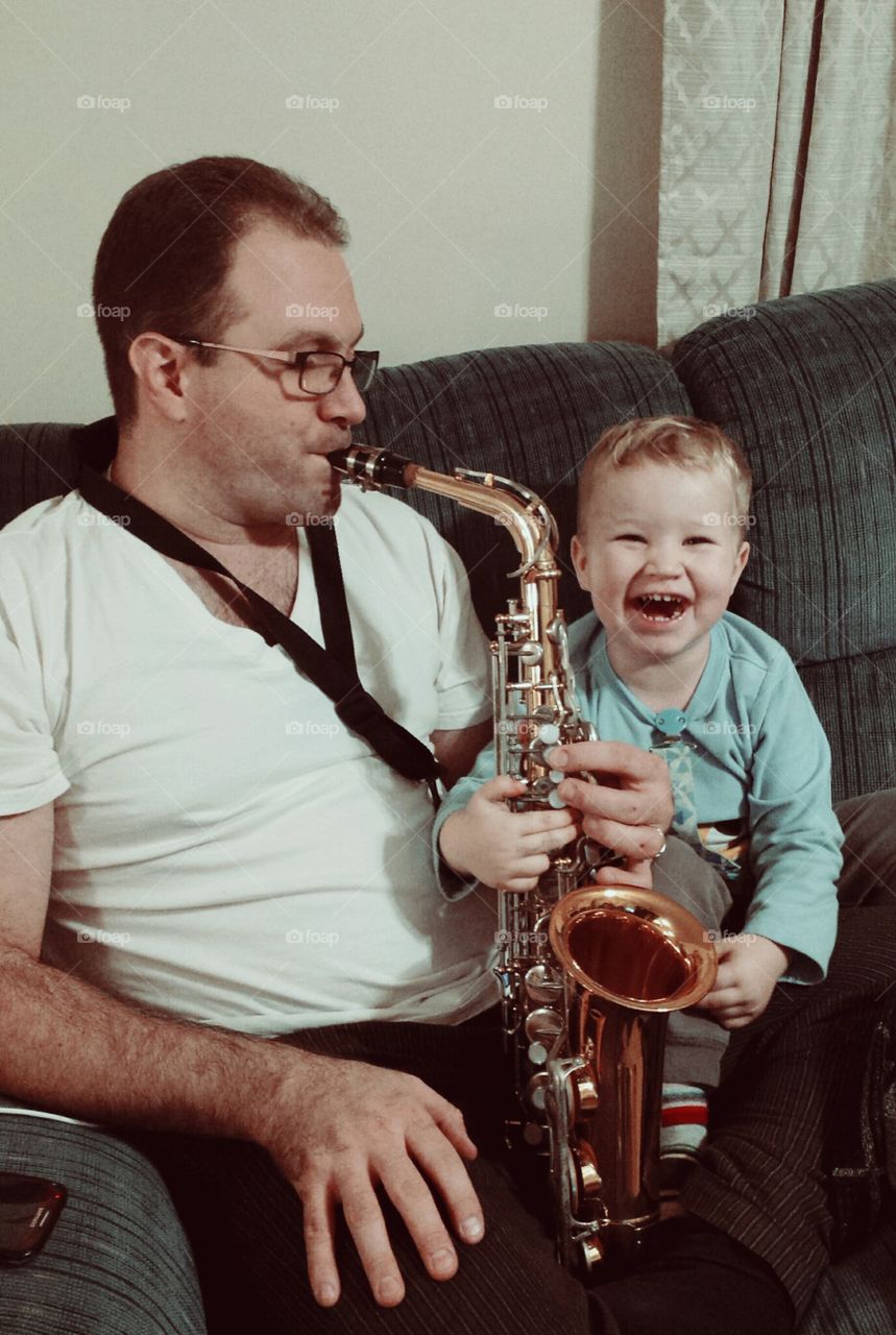 learning the saxophone. my husband showing my son how he plays the sax.  