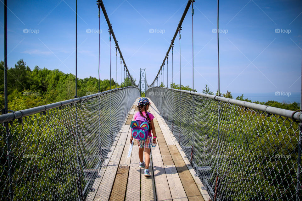 Cute little girl is walking on a suspension bridge