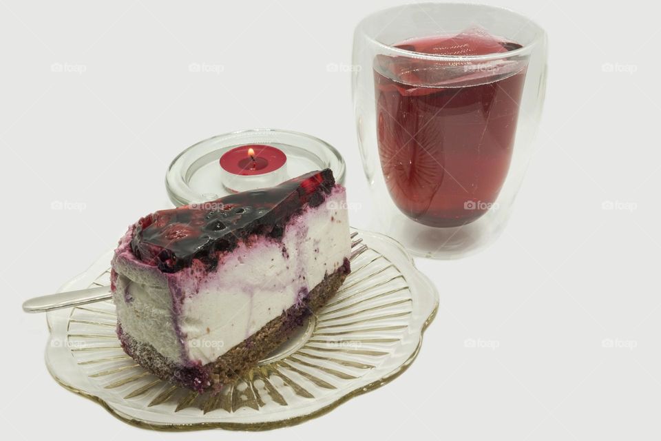 Piece of delicious jelly fruit cake, hibiscus tea and candle. Viva magenta