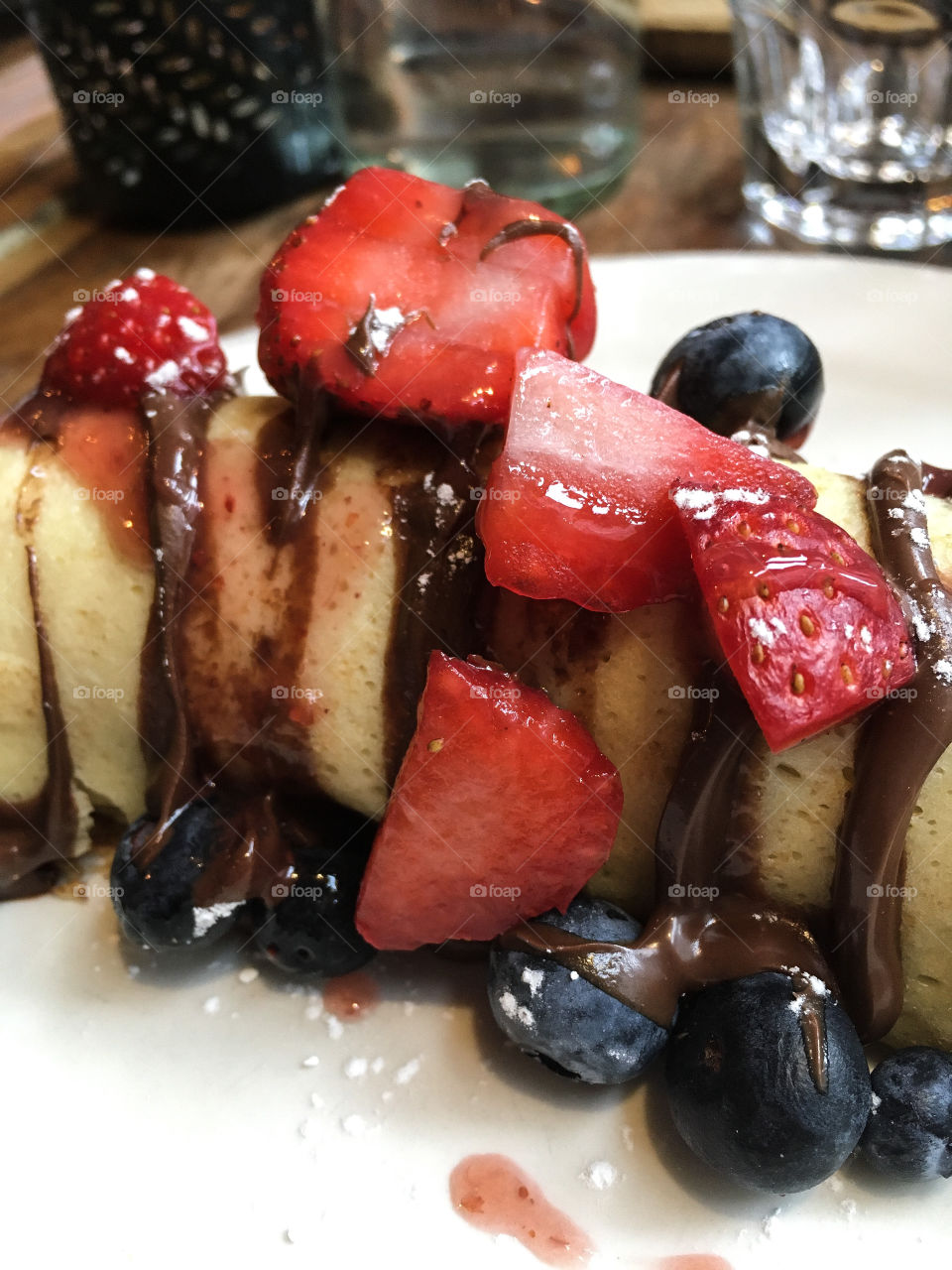Fruity fruits on top of a crepe with chocolate sauce and powdered sugar.  Delicious and almost healthy! 