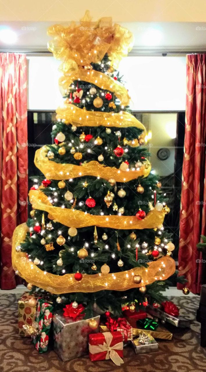 Large Christmas tree with multicolored ornaments and gold, metallic garland