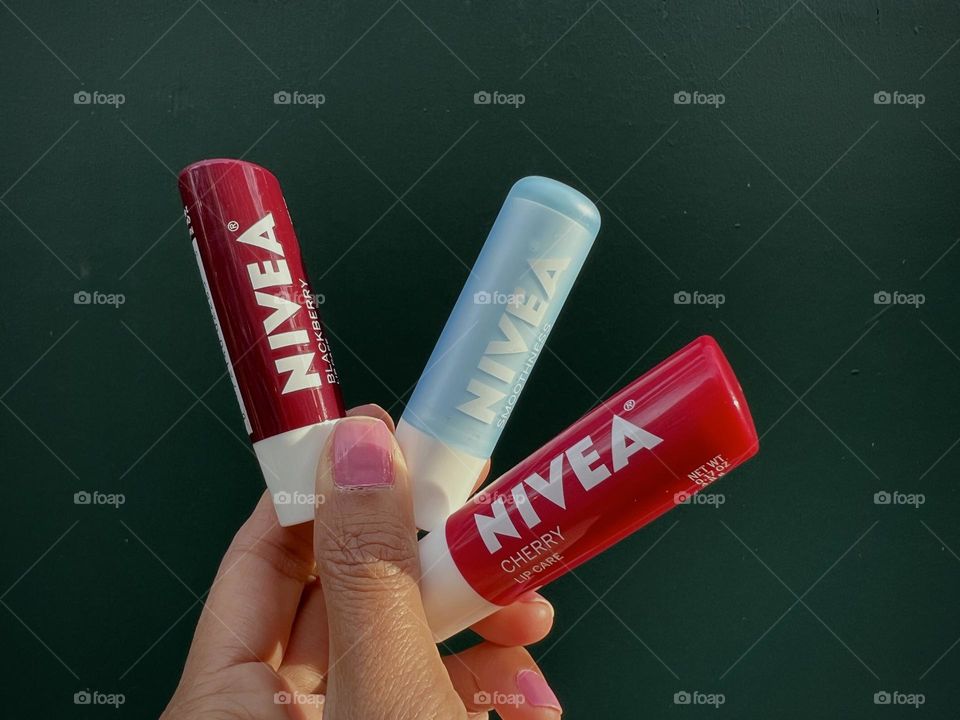 Three Nivea lip balm against green background 