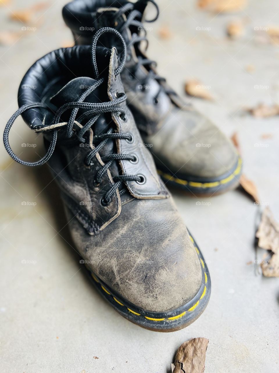 Overhead closeup of thirty year old classic Doc Martens boots on a cement floor with autumn leaves. Symbol of workmanship and lasting quality. @9bachelors Instagram