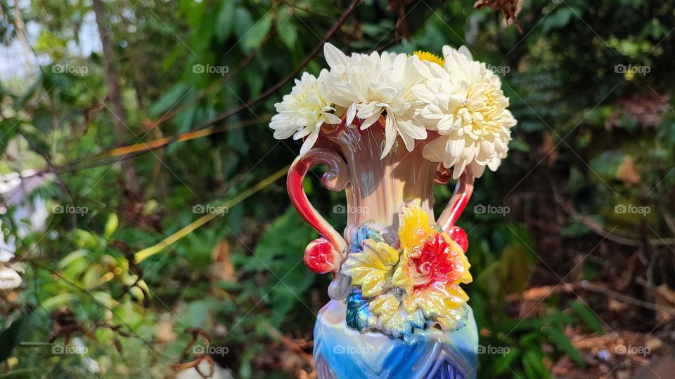 Beautiful white flowers in a colourful flowerpot with a flower sculpture