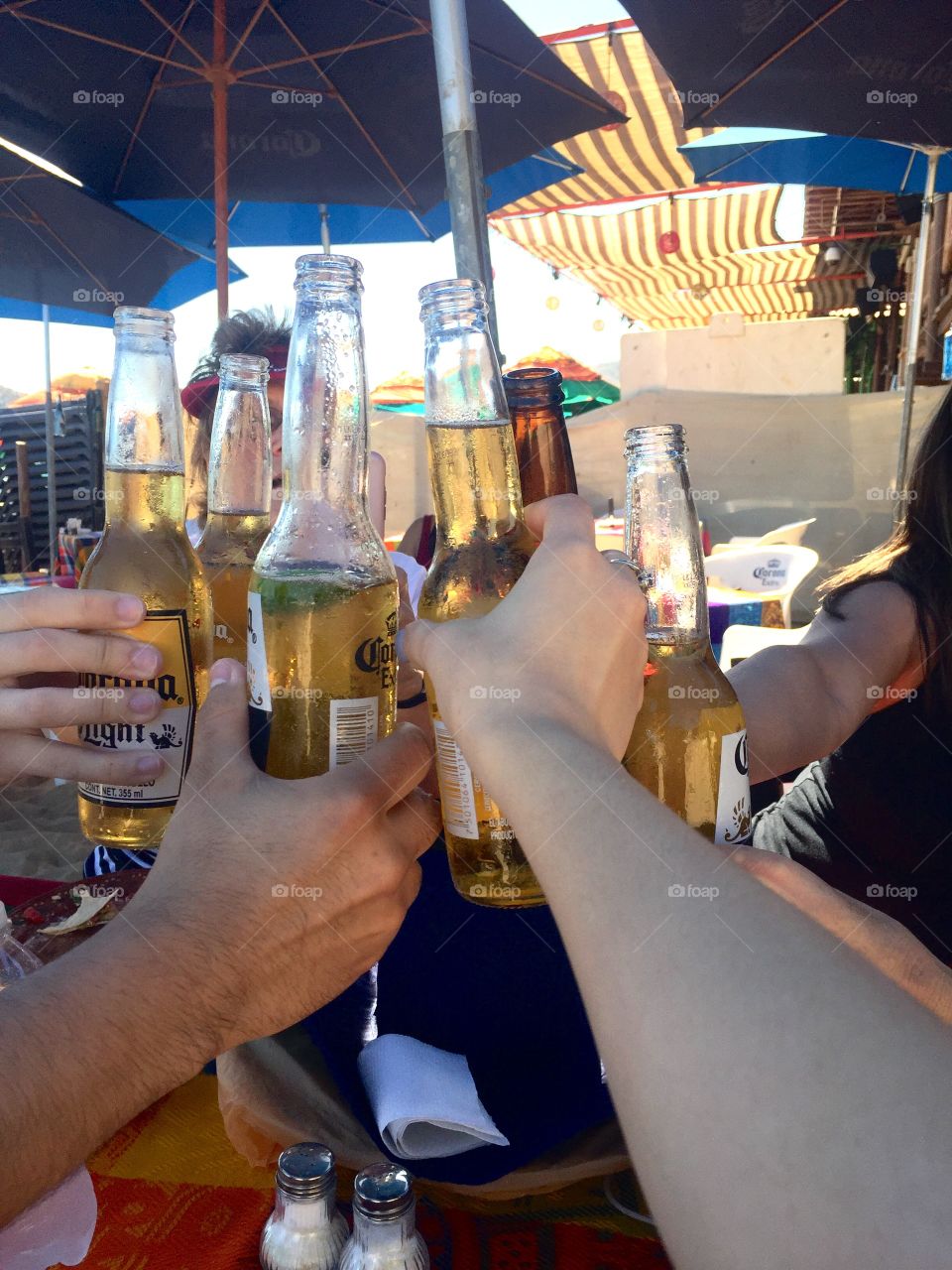 Group of people raising their Corona beer bottles to cheer to good times on vacation in Cabo San Lucas in the Mexican Riviera