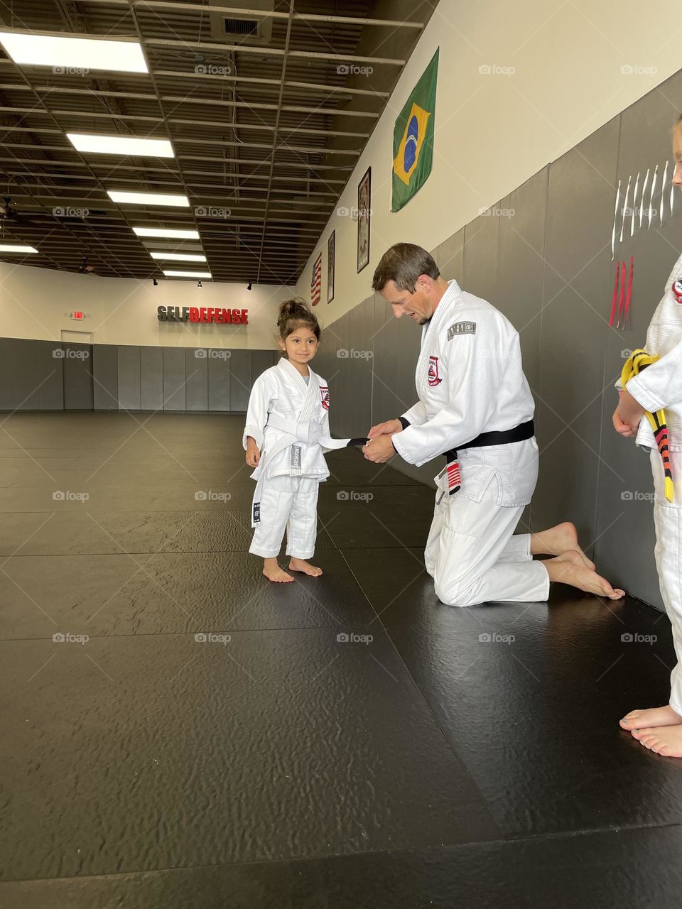 Girl receives stripe on belt in Jiu Jitsu, working hard in martial arts, little girl is excited about Jiu Jitsu 