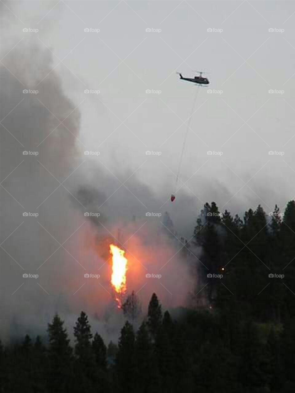 helicopter flying over fire helping to put it out