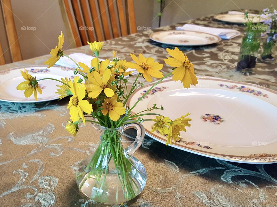 Fresh wildflowers in glass containers decorate a spring dining room table