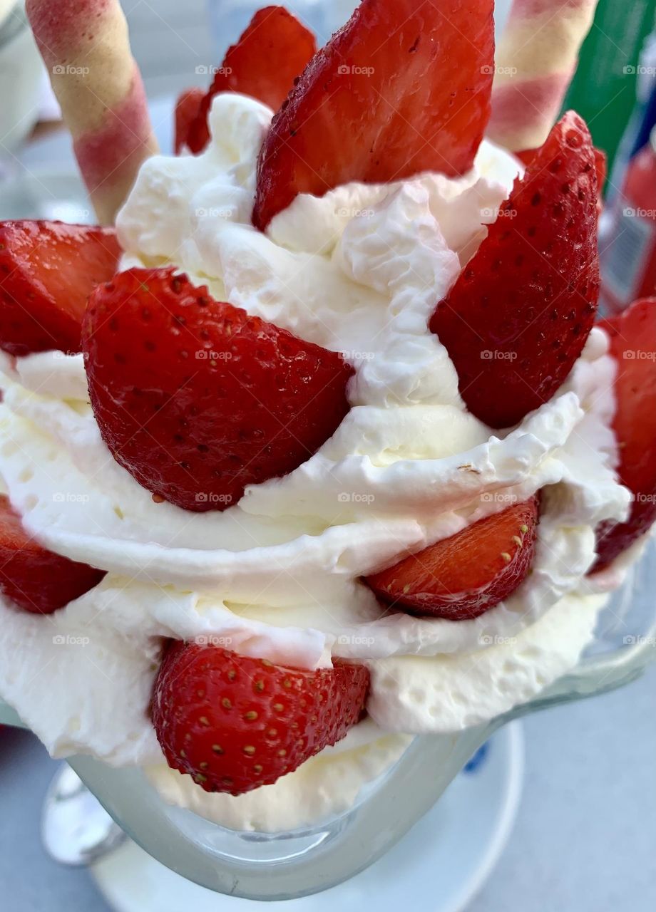 Yummy strawberries with whipped cream on crystal bowl decorated with biscuits 