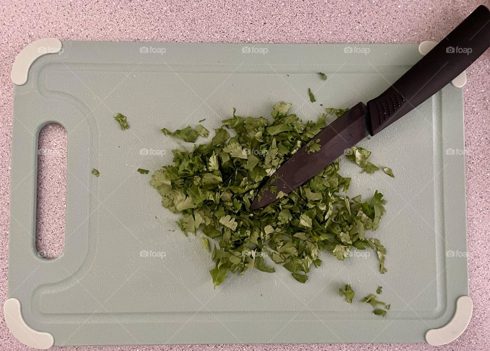 Cutting up cilantro for dinner, cooking with cilantro, cilantro on the cutting board 