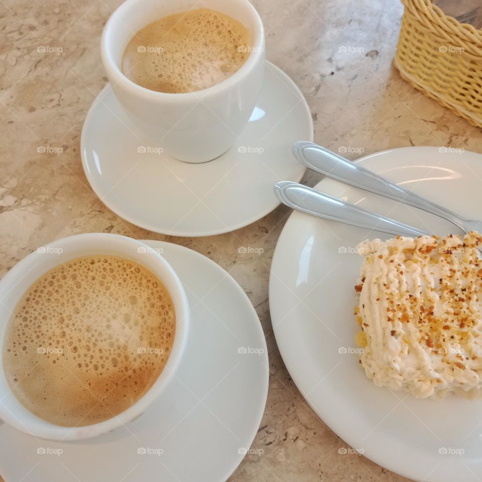 Two cups of simple coffee and milk and a piece of cake