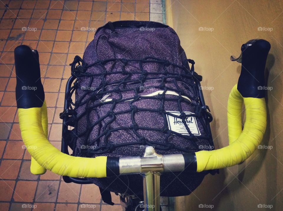 Herchel backpack on a front bicycle rack on a black singlespeed soviet commuter bicycle with yellow handlebar tape in Moscow, Russia