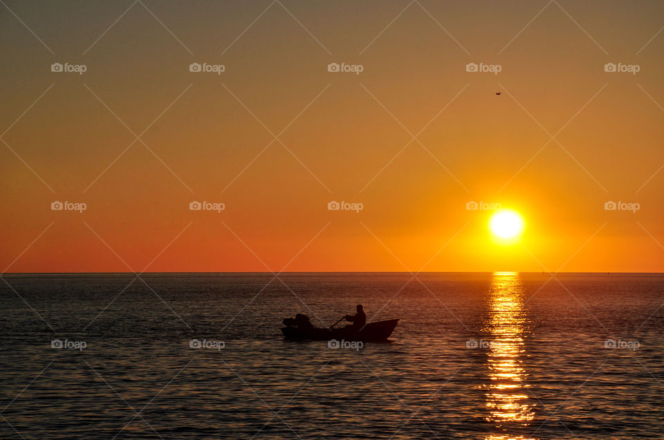 The boat with fishermen in the sea at sunset
