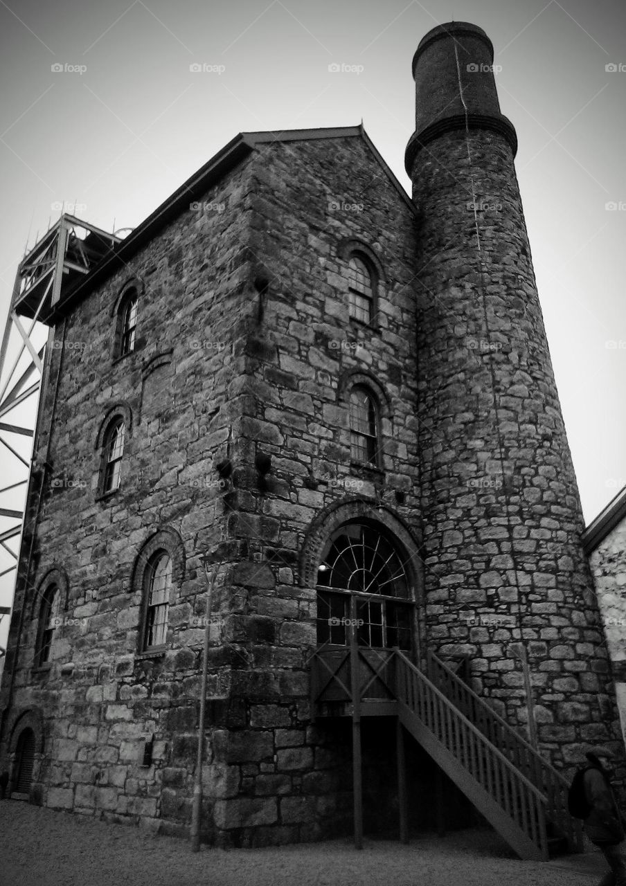 A black and white photograph of a stone building that used to be used in deep mining.