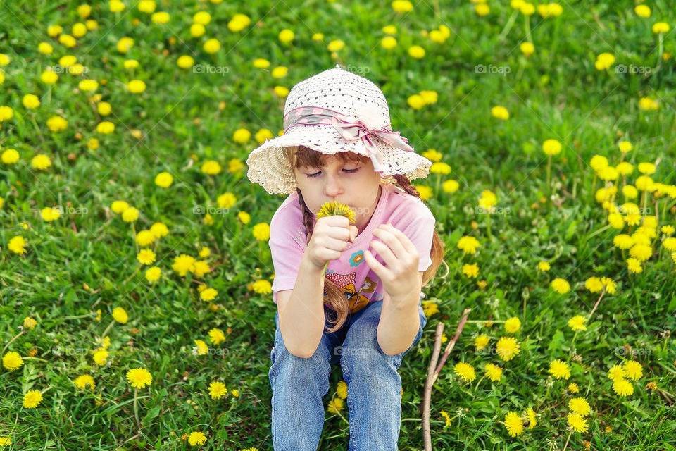 Summer, field of dandelions, portrait of the girl, girl is smelling flowers