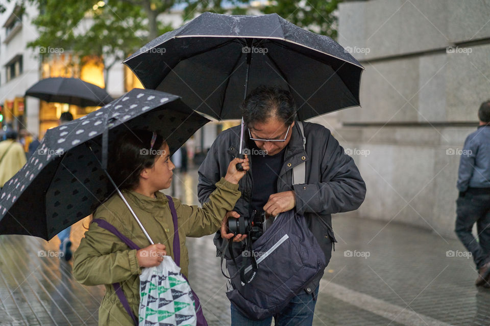 Teenage girl and man with camera in rainy season