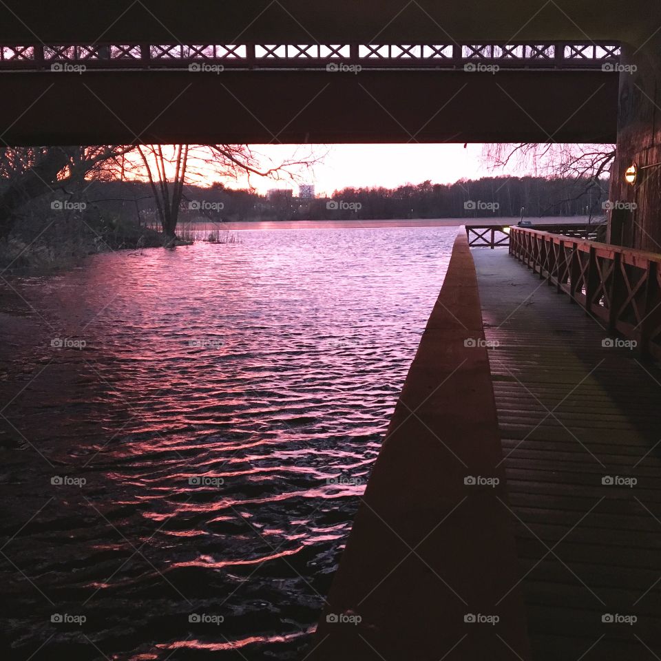 Small walking bridge along purple reflections at waterline