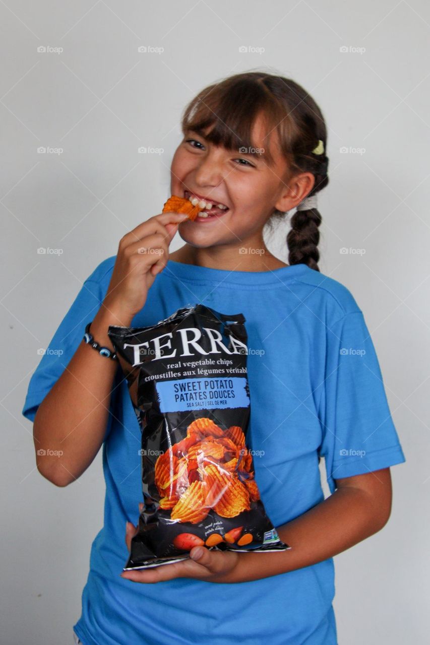 Cute happy girl with a bag of chips