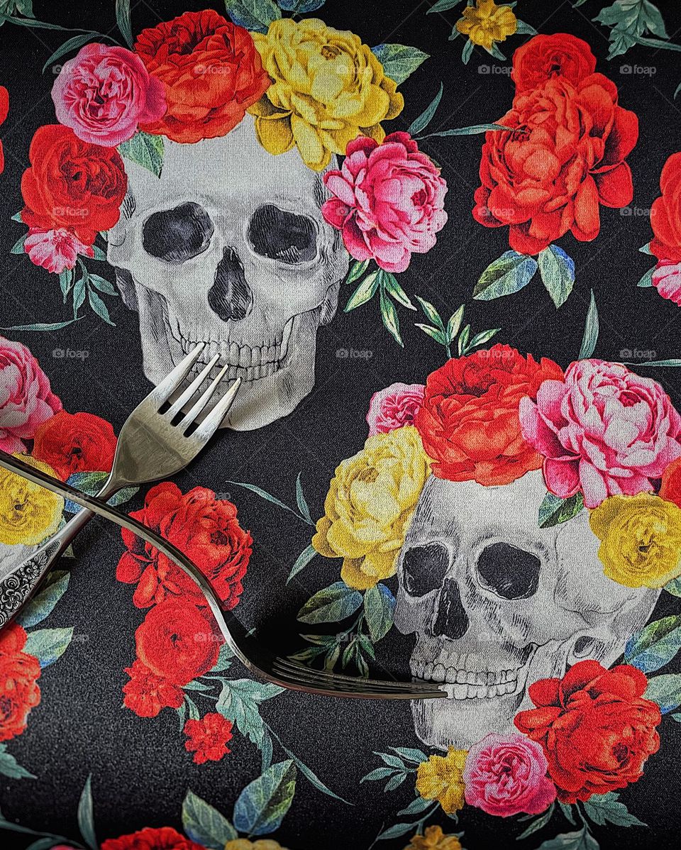 Forks feeding skulls, forks posed in feeding positions for skulls wearing flowers, skulls flowers and forks, fun and imaginative ways to use forks, eating utensils used differently 