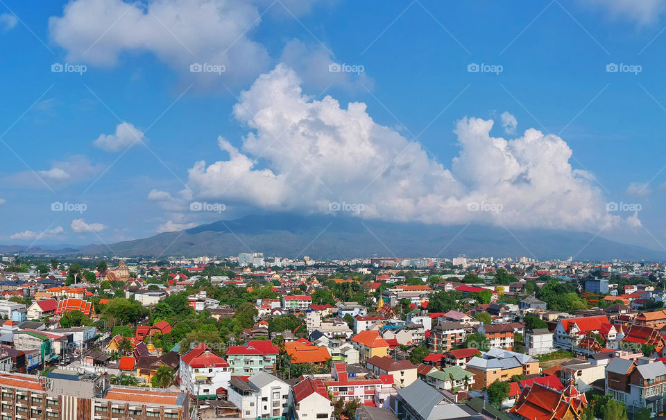 Beautiful aerial view of Chiang Mai cityscape in the day time with Doi Suthep mountain, blue sky and whit clouds in the background. Chiang Mai, Northern Thailand.