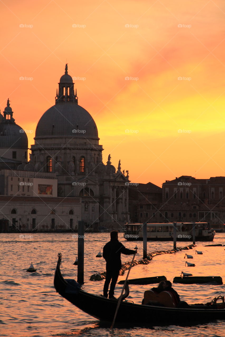 A couple on a gondolier at sunset in Venice.
