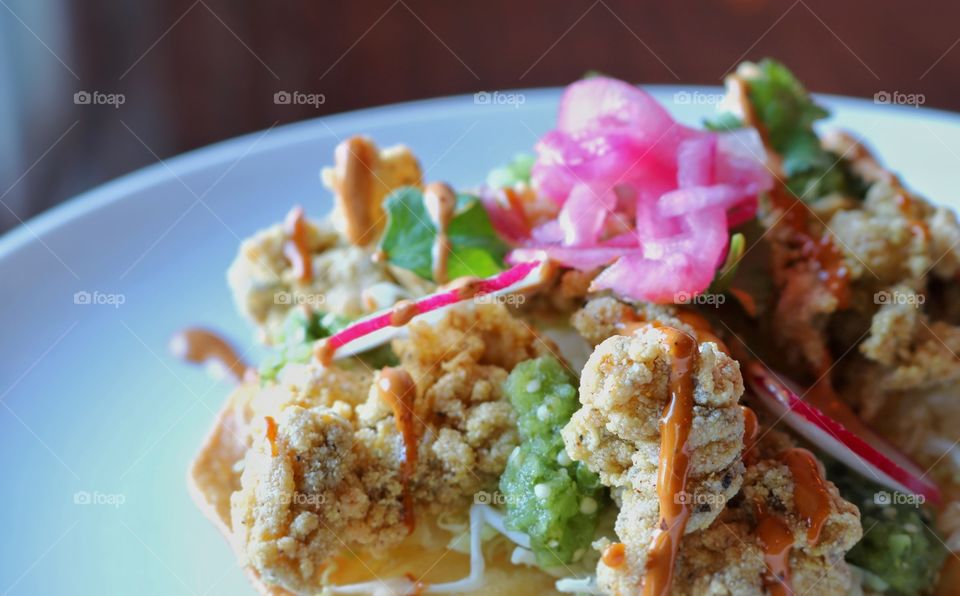 Fried Oyster Tostada with roasted Tomatillo salsa, pickled onions, & Guajillo sauce 