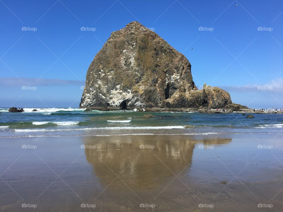 Haystack Rock reflecting into the shallow water.Seaside , Oregon 