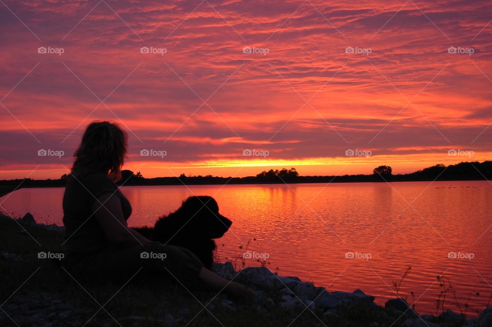 Woman and her Newfoundland enjoying the sunset over Findlay lake, Ohio