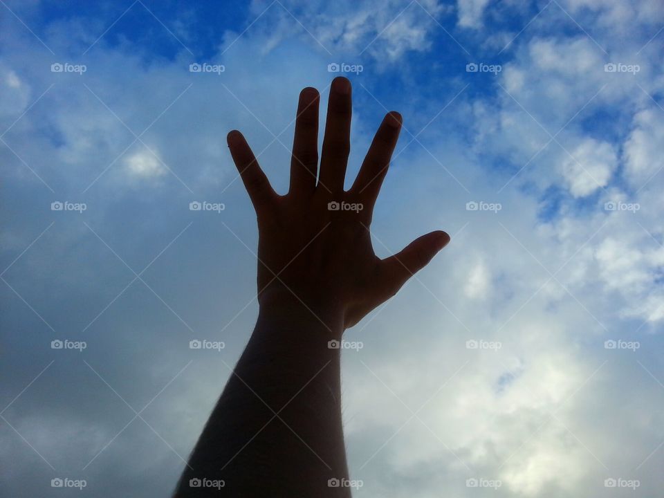 Close-up of hand against cloudy sky