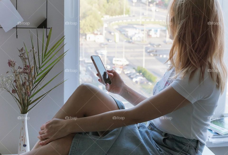 A woman sitting by the window at home 