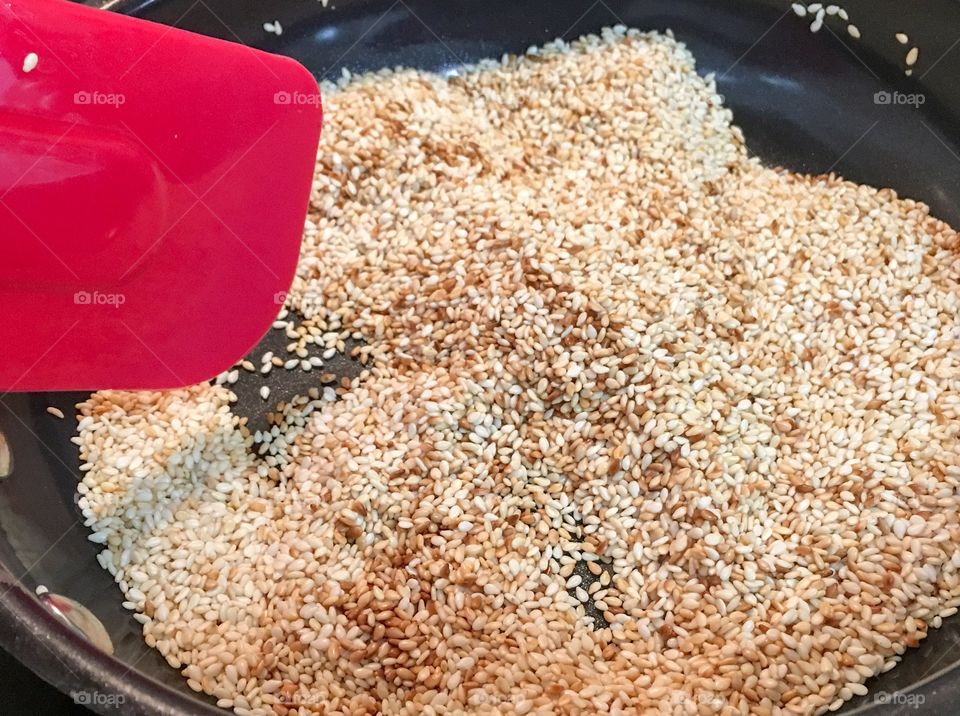 Toasting sesame seeds food prep Asian cuisine red spatula closeup 