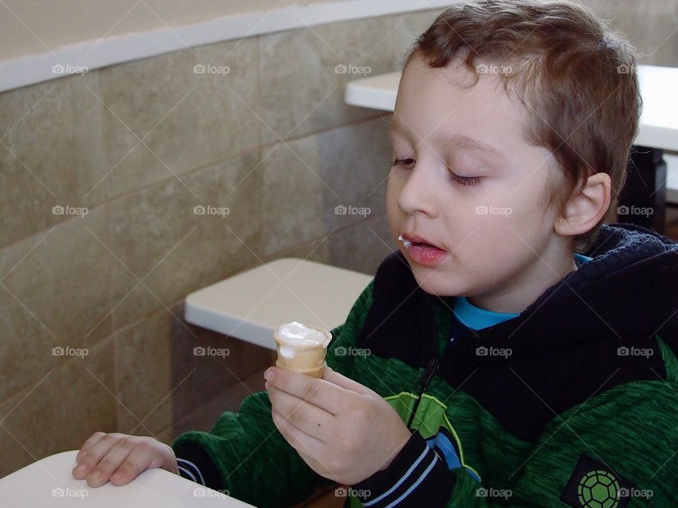 A little boy gets ready to take another bite of his vanilla ice cream cone. 