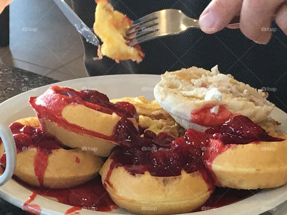 A large serving of waffles Canadian style topped with strawberries and whipped cream