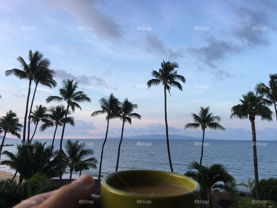 Morning coffee at sunrise  with an amazing ocean view in Maui, you can see palm trees and islands in the distance 