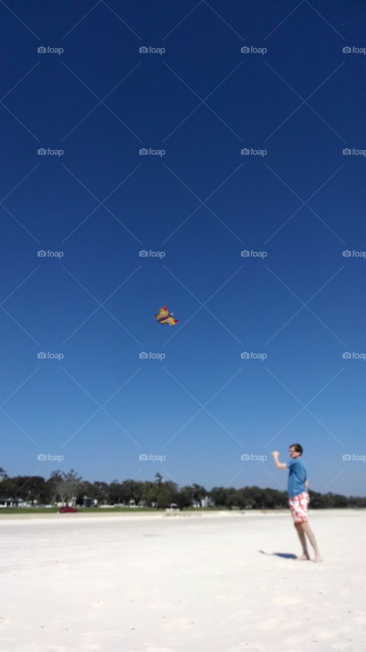 guy flying kite on beach
