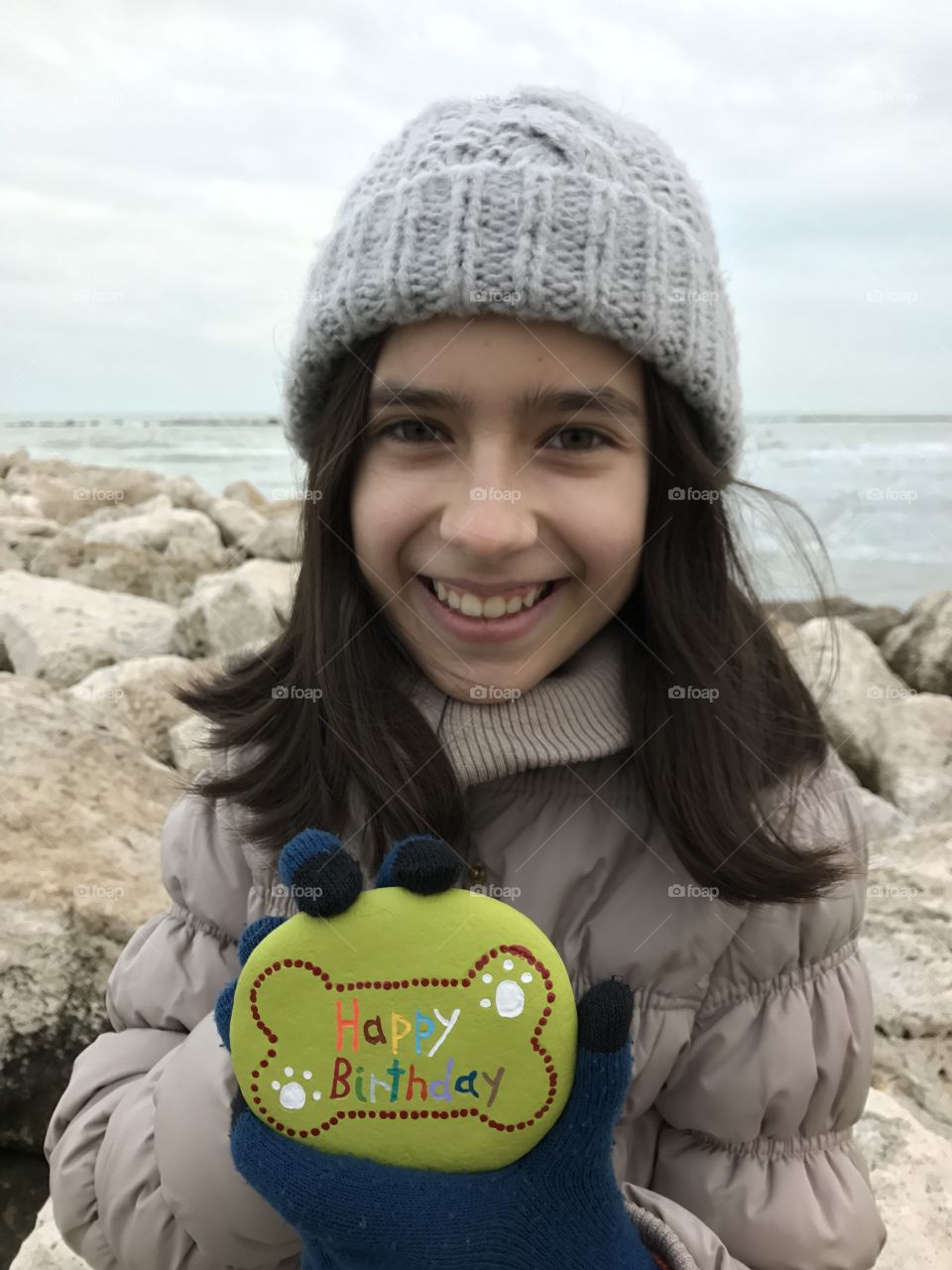 Smiling girl holding pebble stone with text