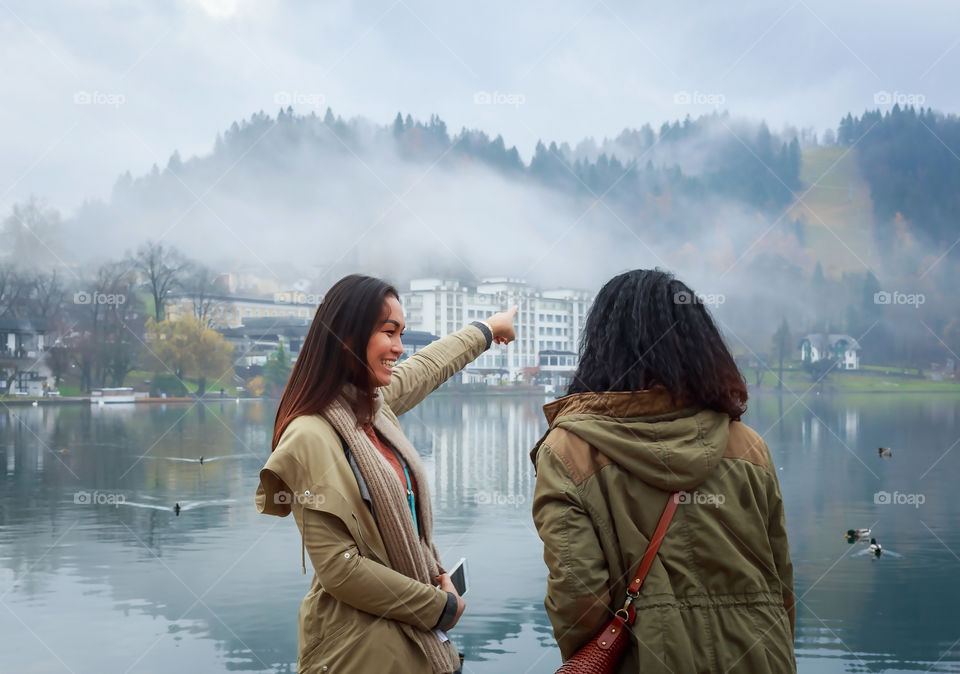 Girl pointing towards mountains and buildings at scenic landscape