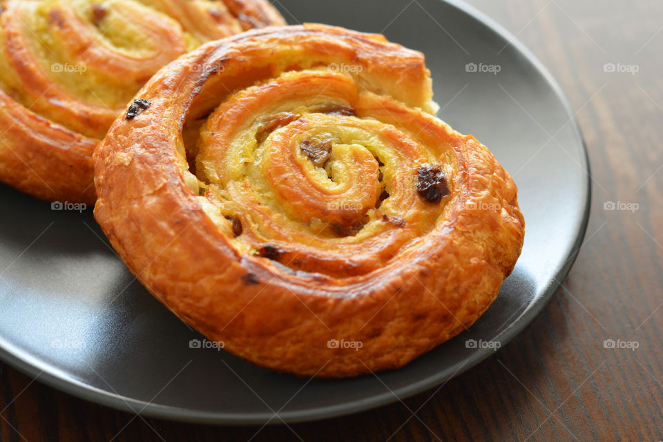 Danish raisin swirls on a black plate.